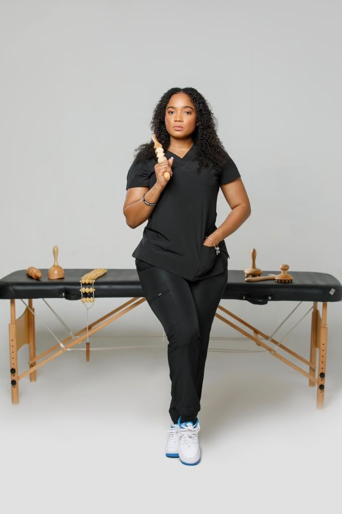 Lou standing in front of a massage table with wooden massage tools